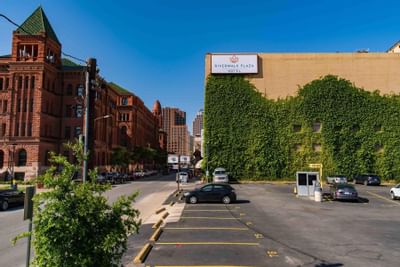 Exterior view of The Riverwalk Plaza Hotel covered in greenery with the city skyline and a clear sky