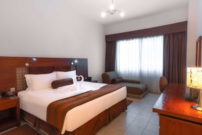 Work desk facing bed with seating by the window in a room at Tamani Marina Hotel