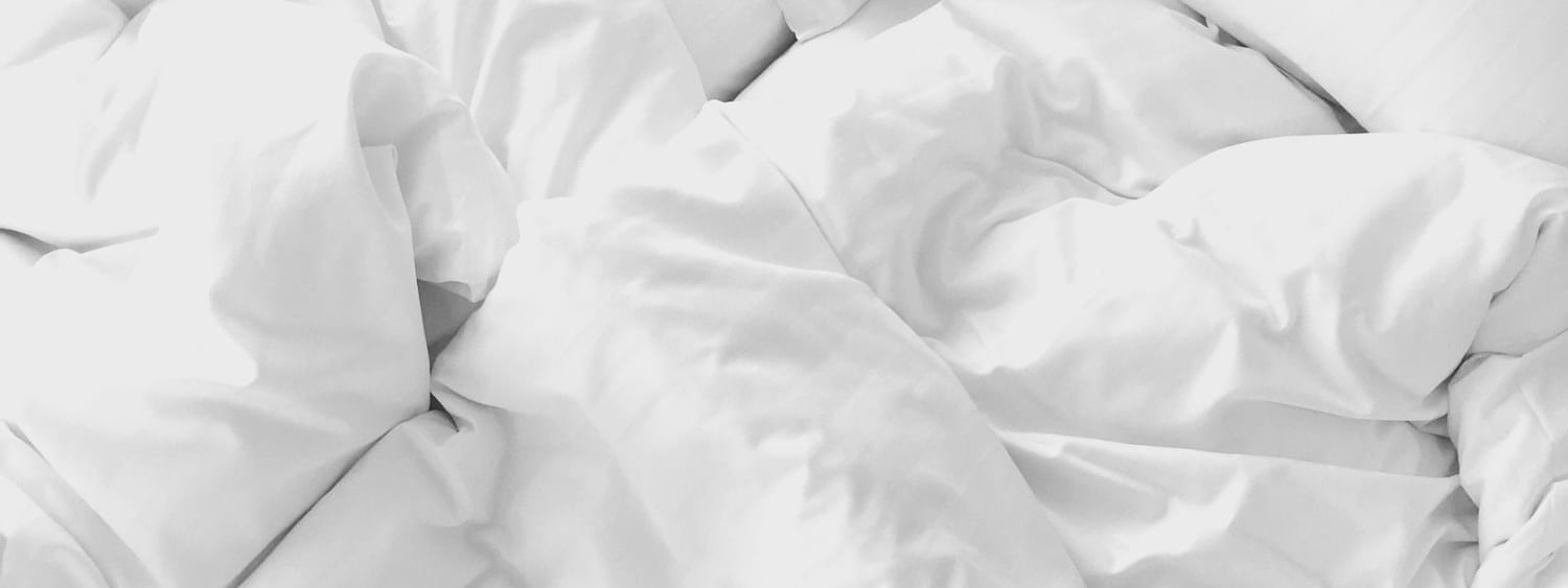 Overhead close-up of white bedding with crumpled sheets and pillows ready for a restful stay at Novotel Perth Langley