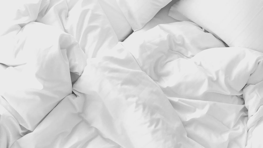Overhead close-up of white bedding with crumpled sheets and pillows ready for a restful stay at Novotel Perth Langley