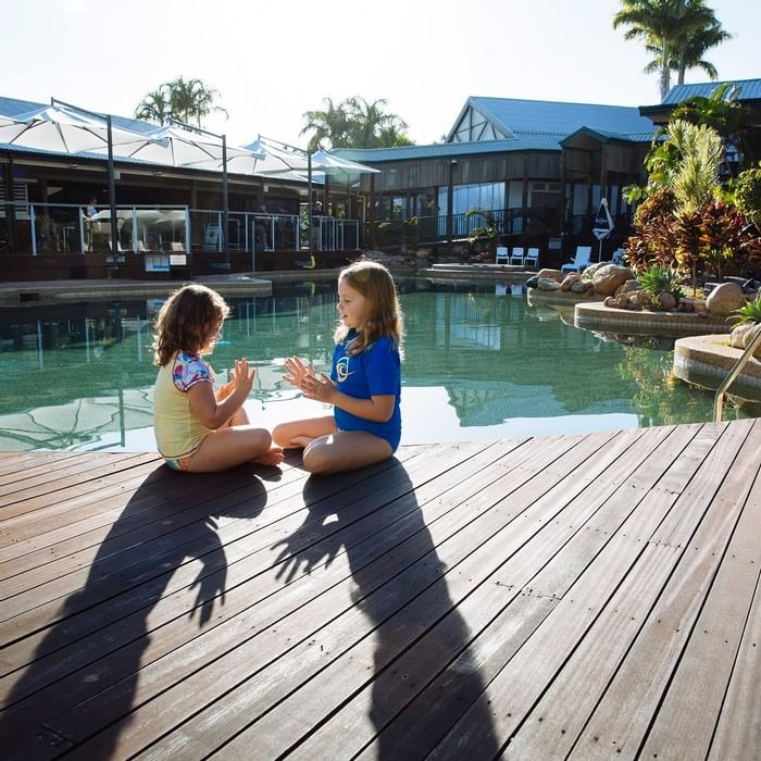 Two children playing on a wooden deck by a pool at Mercure Hotel Townsville