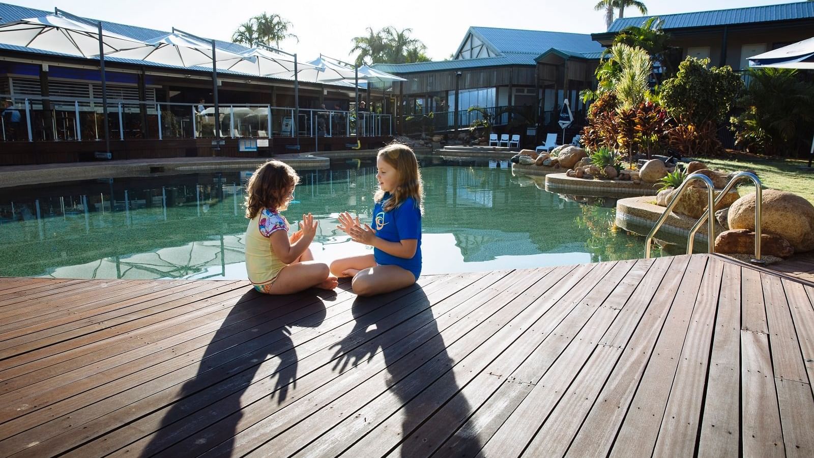 Two children playing on a wooden deck by a pool at Mercure Hotel Townsville