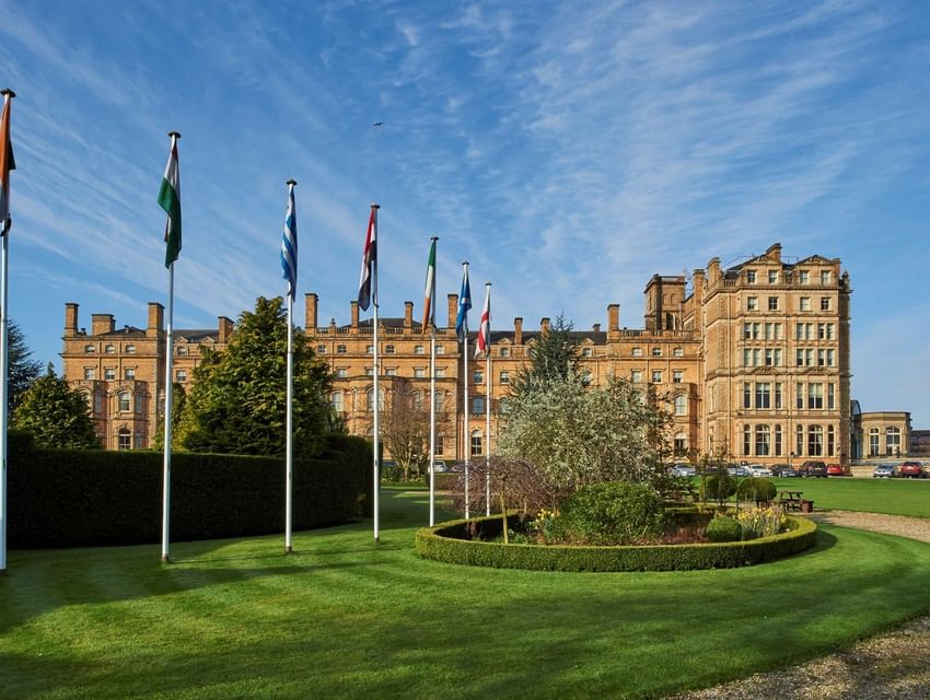 Impressive Victorian architecture of The Milner York hotel with bright blue sky, manicured lawns, and flags flying in England