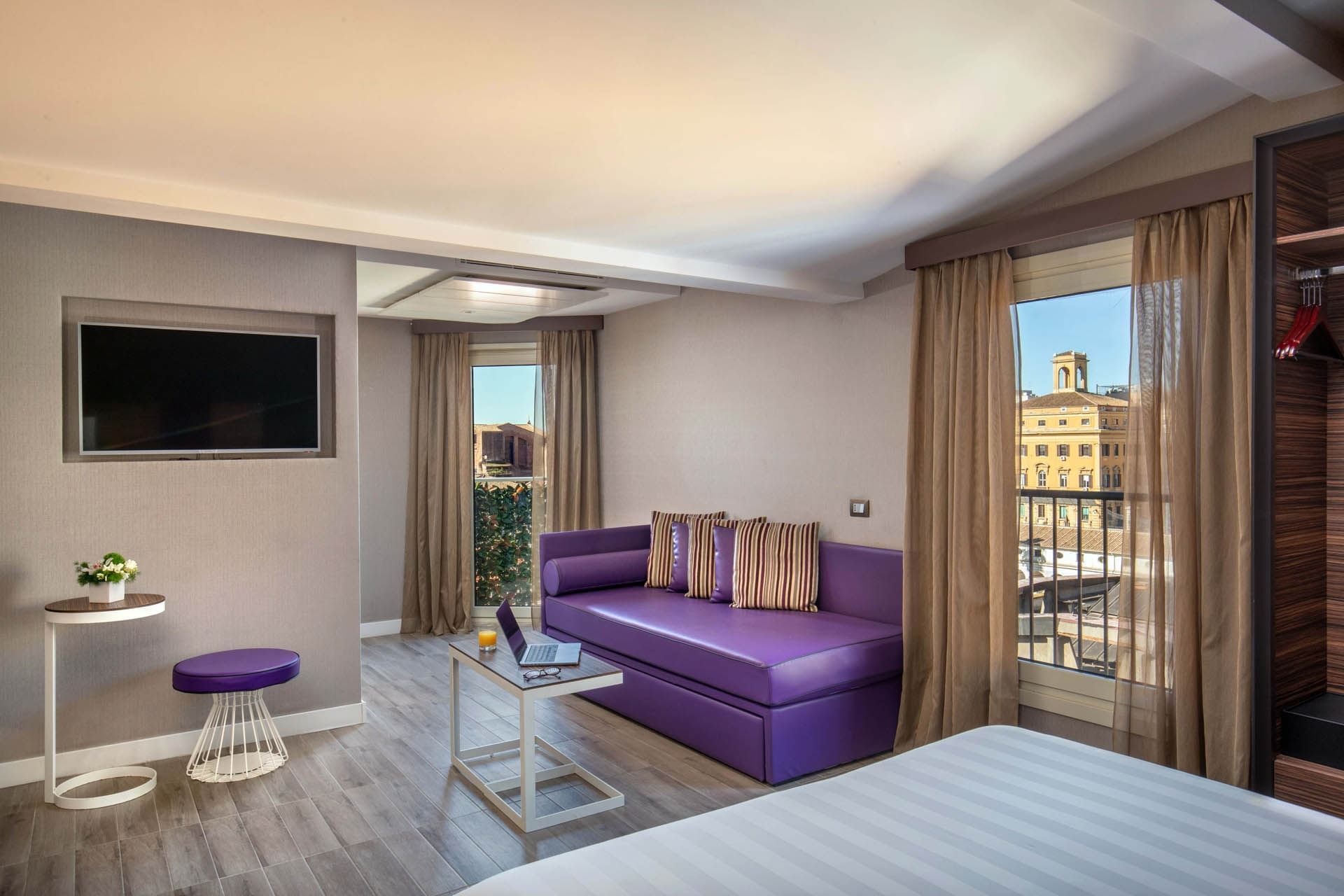 TV lounge by the windows with a bed and wooden floors in the Republic View Suite at The Republic Hotel