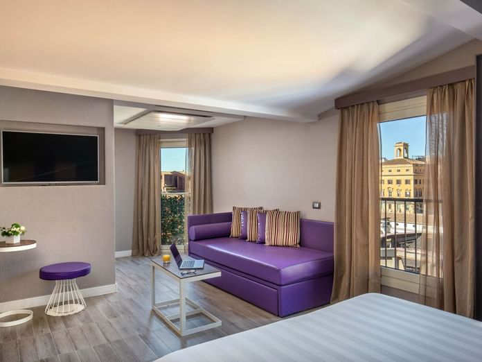 The Republic View Suite featuring a purple couch, a table, a laptop, and windows with a city view at The Republic Hotel