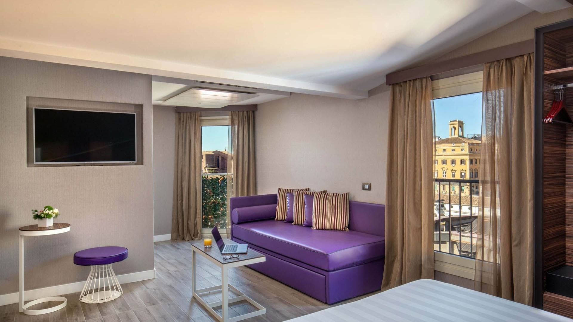 The Republic View Suite featuring a purple couch, a table, a laptop, and windows with a city view at The Republic Hotel