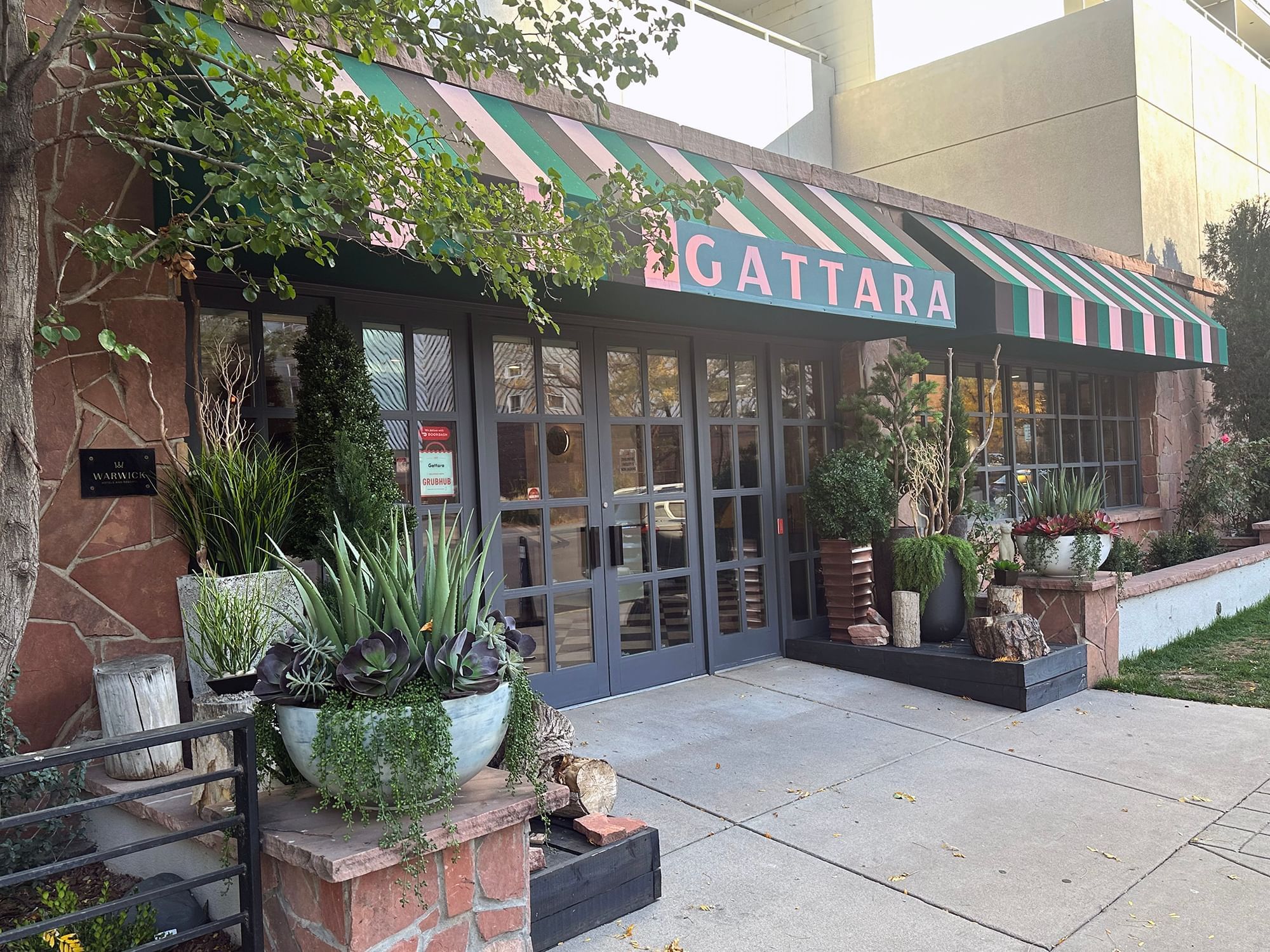 Exterior of Gattara Restaurant with a green surrounding at Warwick Denver