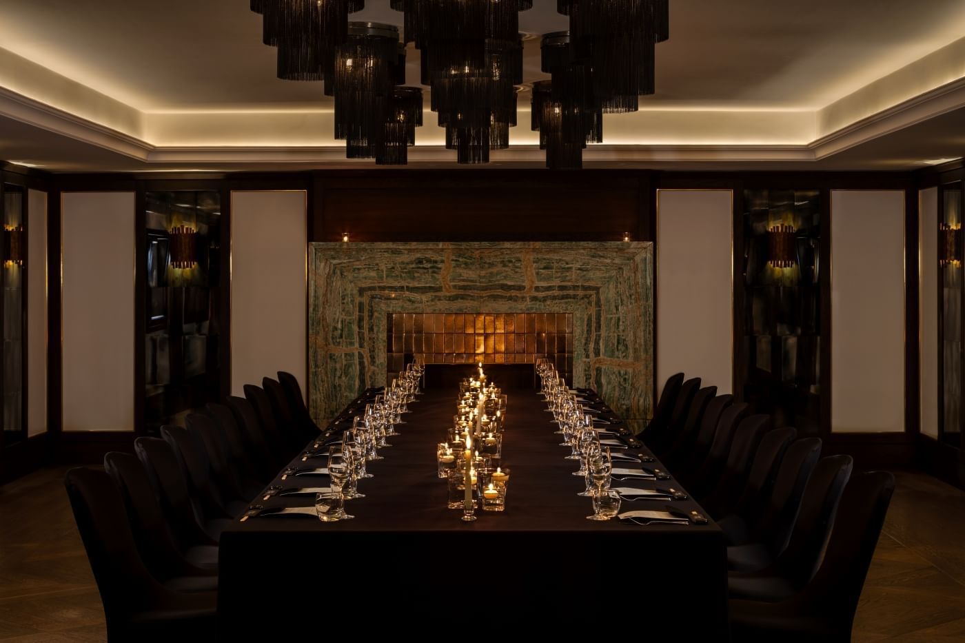 Long dining table set for a banquet with lit candles and glasses for a private event at The May Fair Hotel, London.