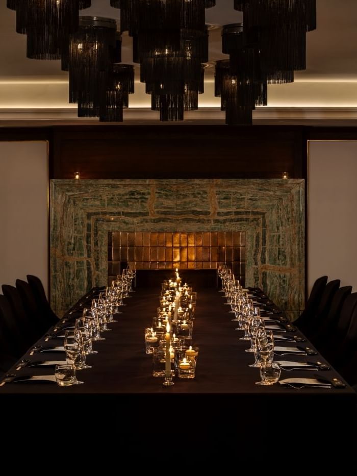Long dining table set for a banquet with lit candles and glasses for a private event at The May Fair Hotel, London.