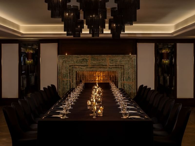 Long dining table set for a banquet with lit candles and glasses for a private event at The May Fair Hotel, London.