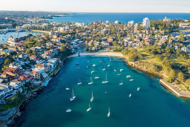 Aerial view of Little Manly Cove near Elysium Manly featuring yachts floating in calm, blue waters
