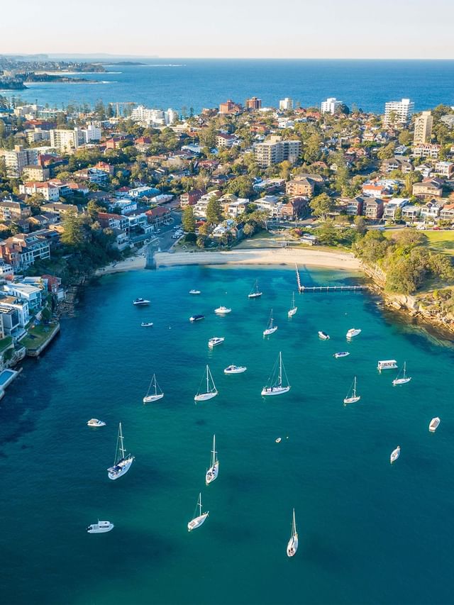 Stunning aerial view of Little Manly Beach bay, featuring boats on the sand near Elysium Manly, a featured hotel in Manly