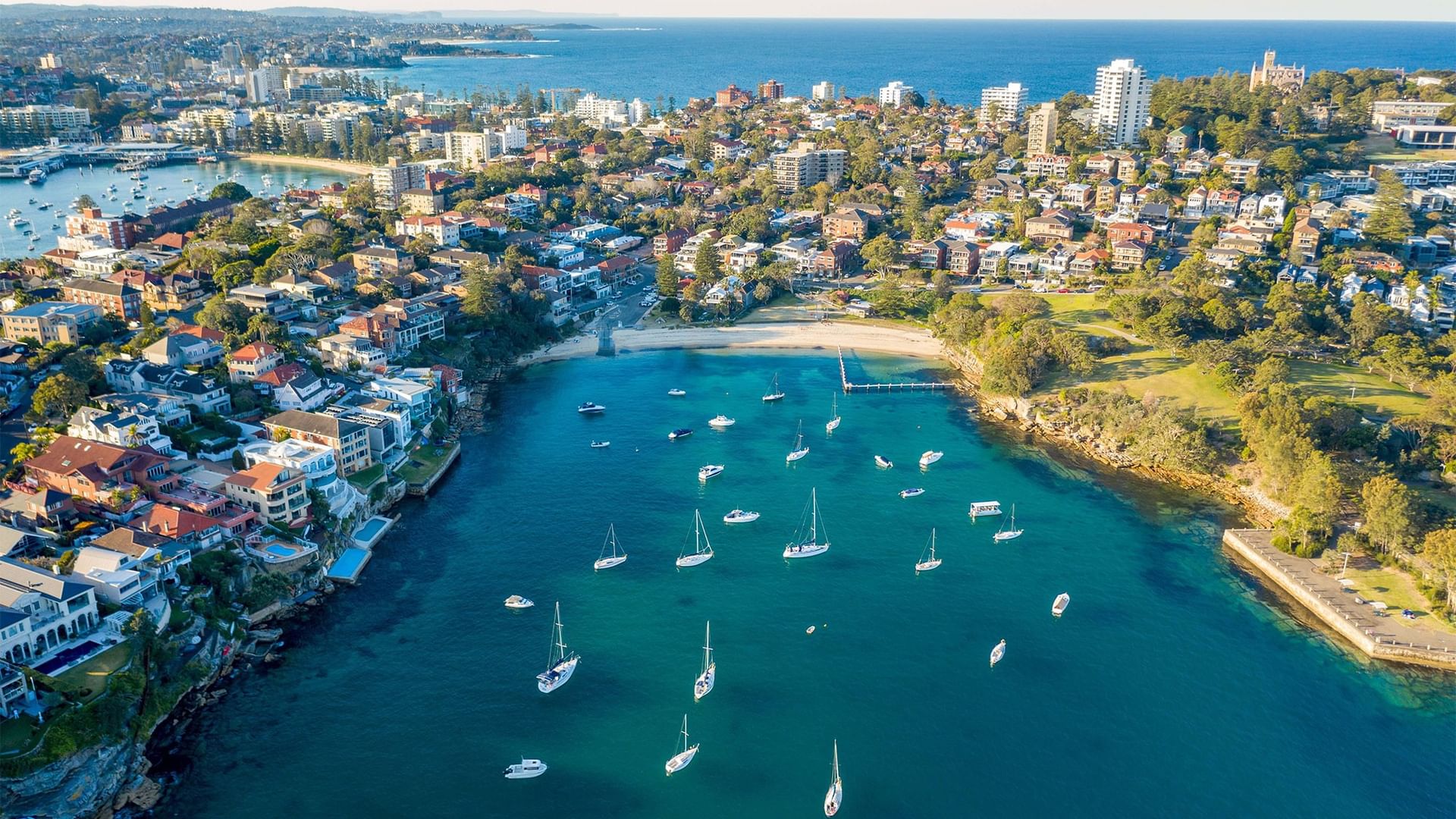 Stunning aerial view of Little Manly Beach bay, featuring boats on the sand near Elysium Manly, a featured hotel in Manly