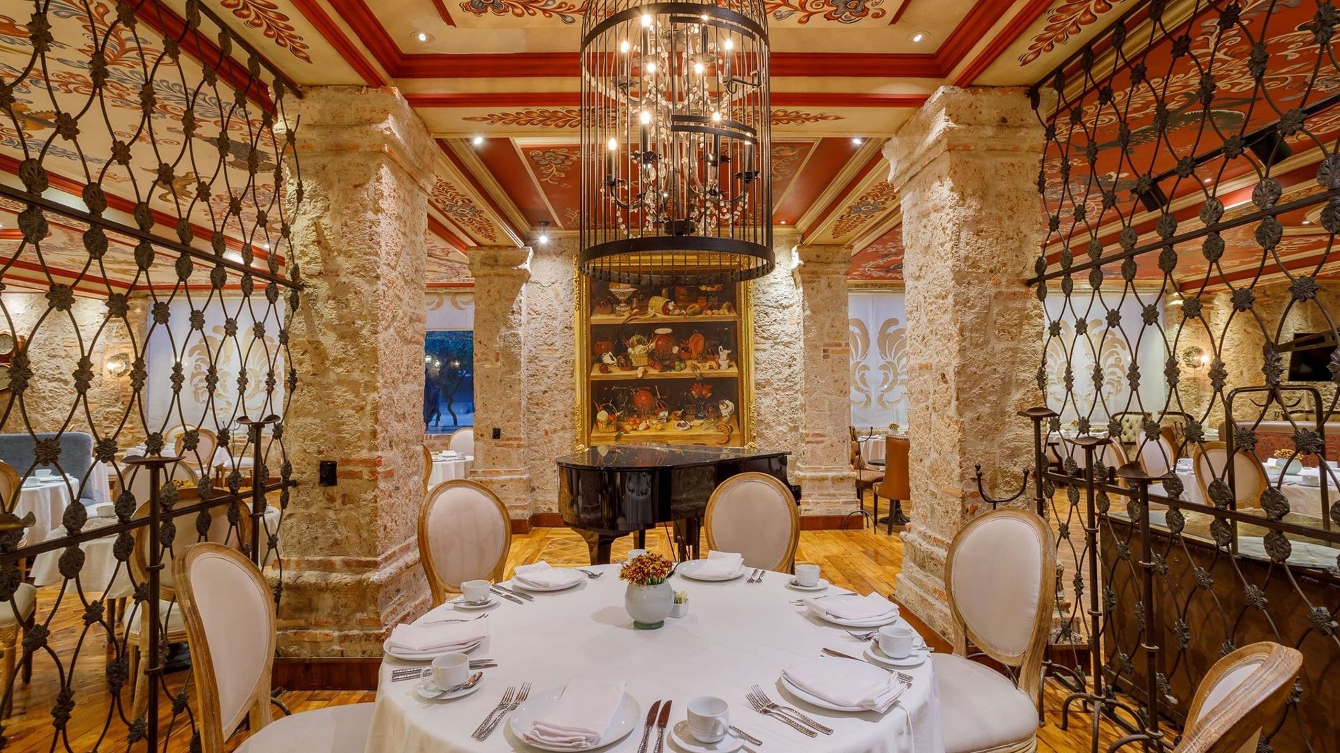 Tierra Mia restaurant with ornate wrought iron screens and a grand piano in the center at Quinta Real Guadalajara