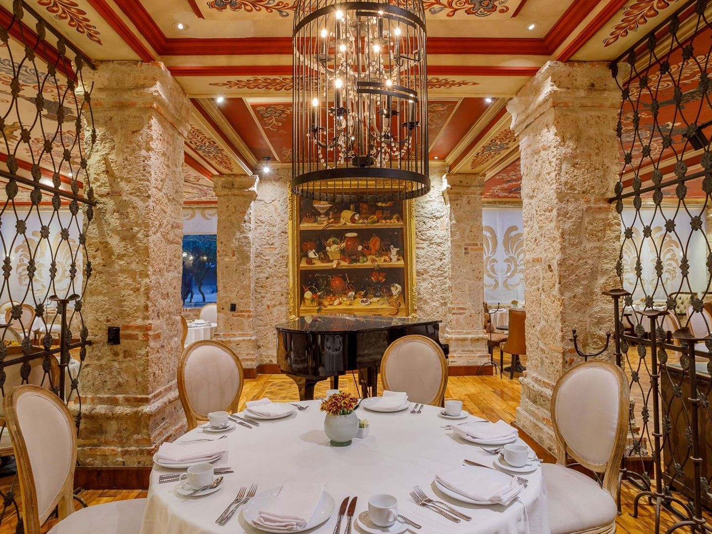 Tierra Mia restaurant with a black grand piano, stone pillars, and ornate murals at Quinta Real Guadalajara