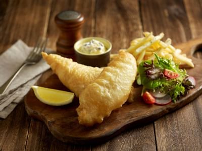Fish and chips served with a side salad on a wooden tray at York Hotel Singapore