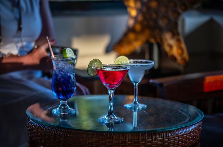 Three colorful cocktails with lime slices on a glass table at Warwick Le Lagon - Vanuatu.