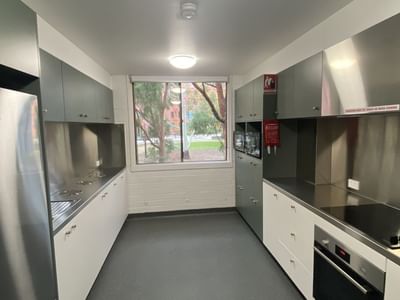 Modern kitchen with stainless steel appliances, white cabinets, and large window at Glenn College.