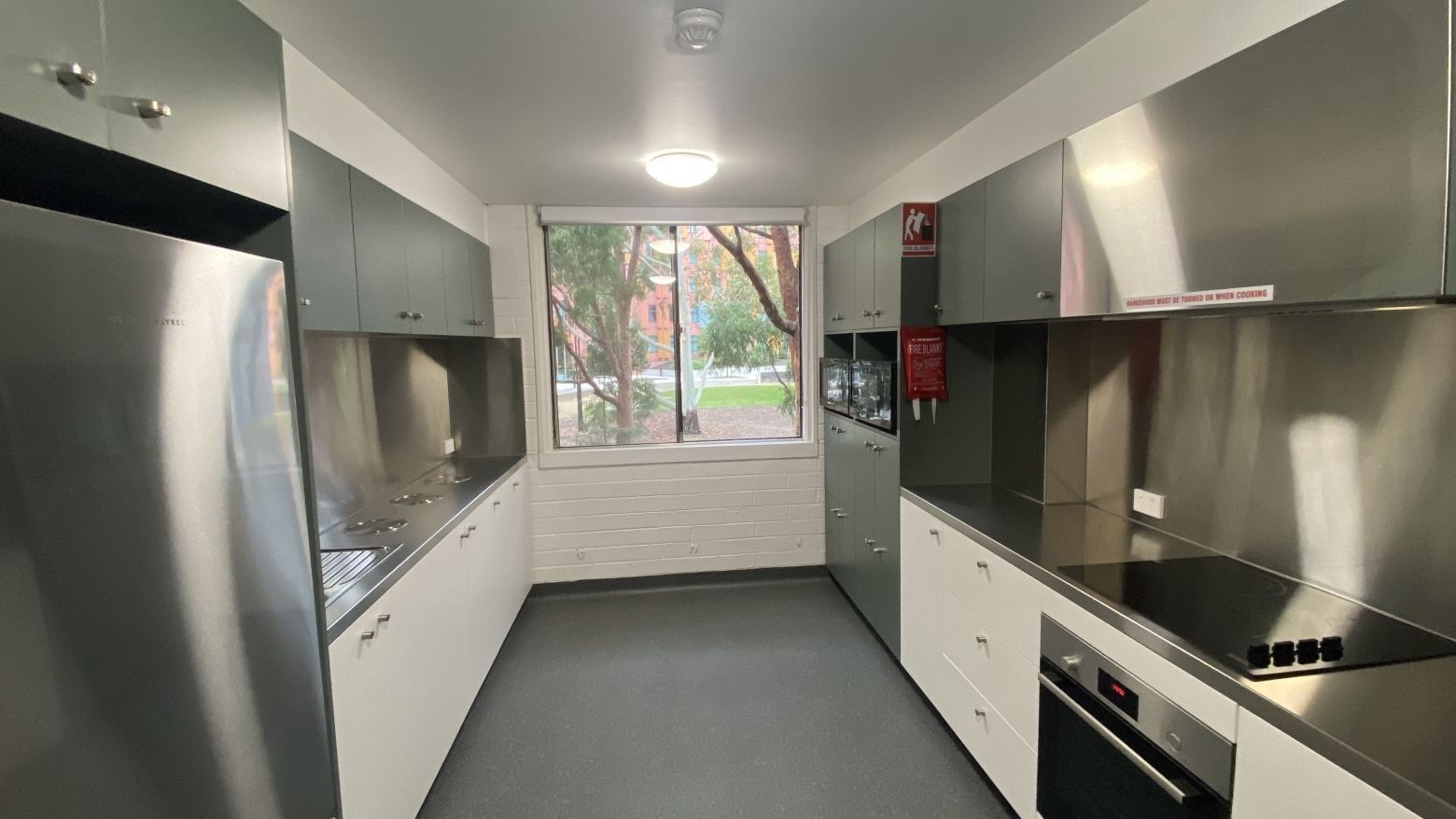 Modern kitchen with stainless steel appliances, white cabinets, and large window at Glenn College.