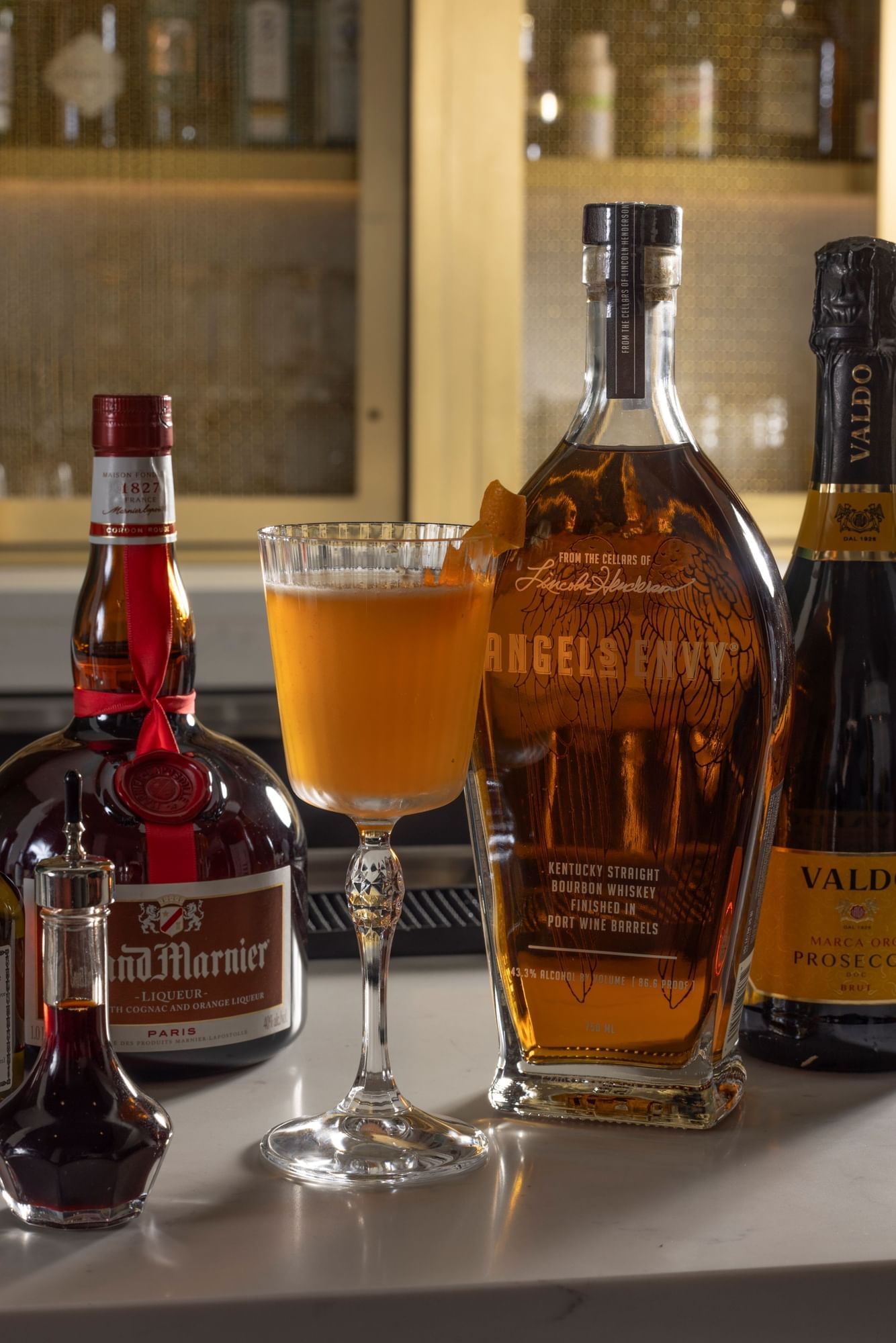 a cocktail glass with an orange drink next to several bottles of liquor