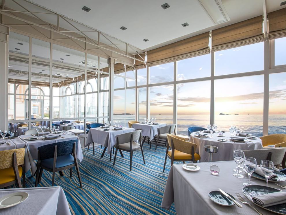Le Cap Horn restaurant featuring dining tables & chairs overlooking the ocean at sunset at Le Grand Hôtel des Thermes