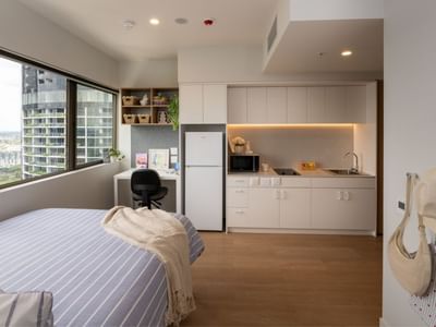 Modern bedroom with city view and kitchenette at UniLodge Brisbane City.
