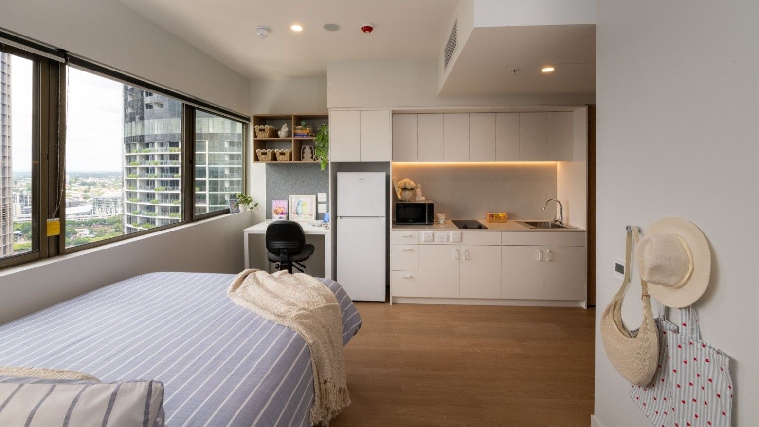 Modern bedroom with city view and kitchenette at UniLodge Brisbane City.