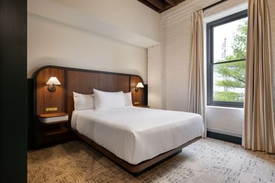 King Room with double bed, headboard, wall-mounted lamp and window at The Delegate Hotel