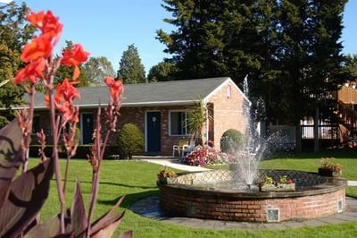 Motel with a blooming garden fountain surrounded by flowers and lush grass at Breezeway Boutique Hotel