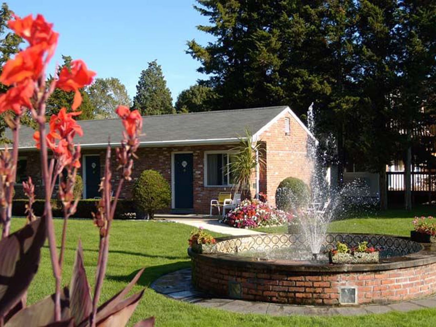 Motel with a blooming garden fountain surrounded by flowers and lush grass at Breezeway Boutique Hotel