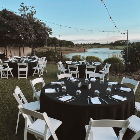 event on lakeside lawn overlooking lake with festoon lighting