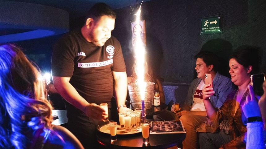 Servicio de botellas con vela de fuente brillante junto a vasos de chupito para invitados en El Rollo de Araiza Palmira