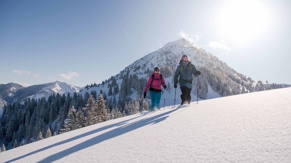 A couple snowshoeing on a mountain near Liebes Rot
