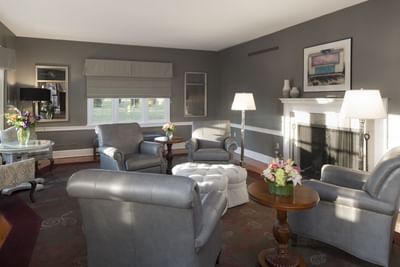 Elegant lounge with gray leather seating, fireplace, and fresh flowers at Aramark Chauncey Conference Center