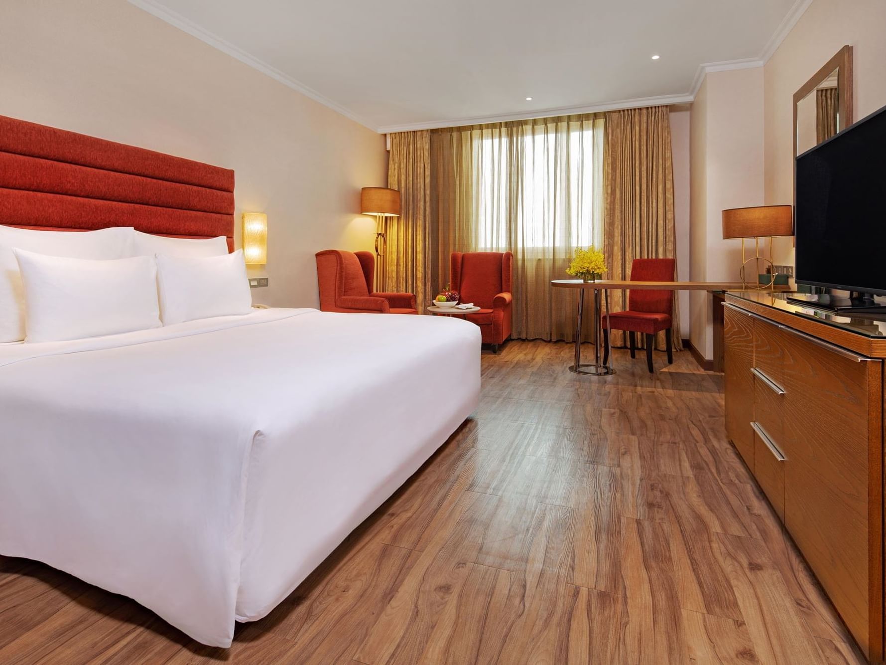spacious hotel room with wood and red cushion furnishings