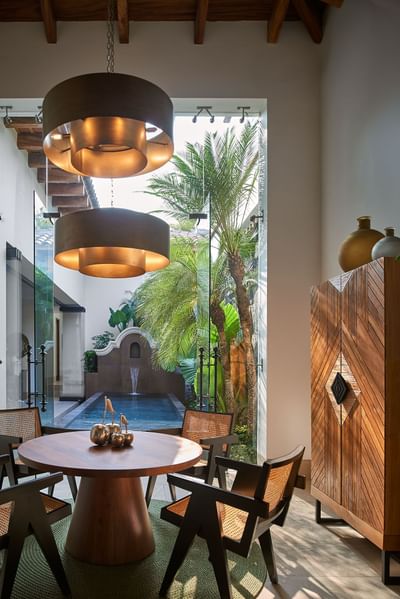 Dining table with chairs and decorative fruit centerpiece, overlooking a pool in Casa Cielo at Singular Signature Residences