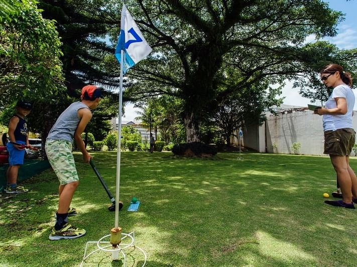 A kid playing ground golf on the greenery at Palau Royal Resort