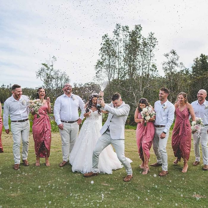 A wedding party popping champagne outdoors with confetti in the air at Mercure Kooindah Waters