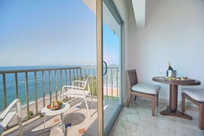 A scenic private resort balcony with a table and chairs overlooking the blue ocean waters.