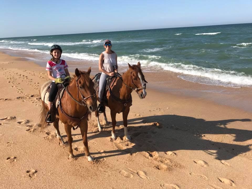 Happy friends on horses wandering the beach.