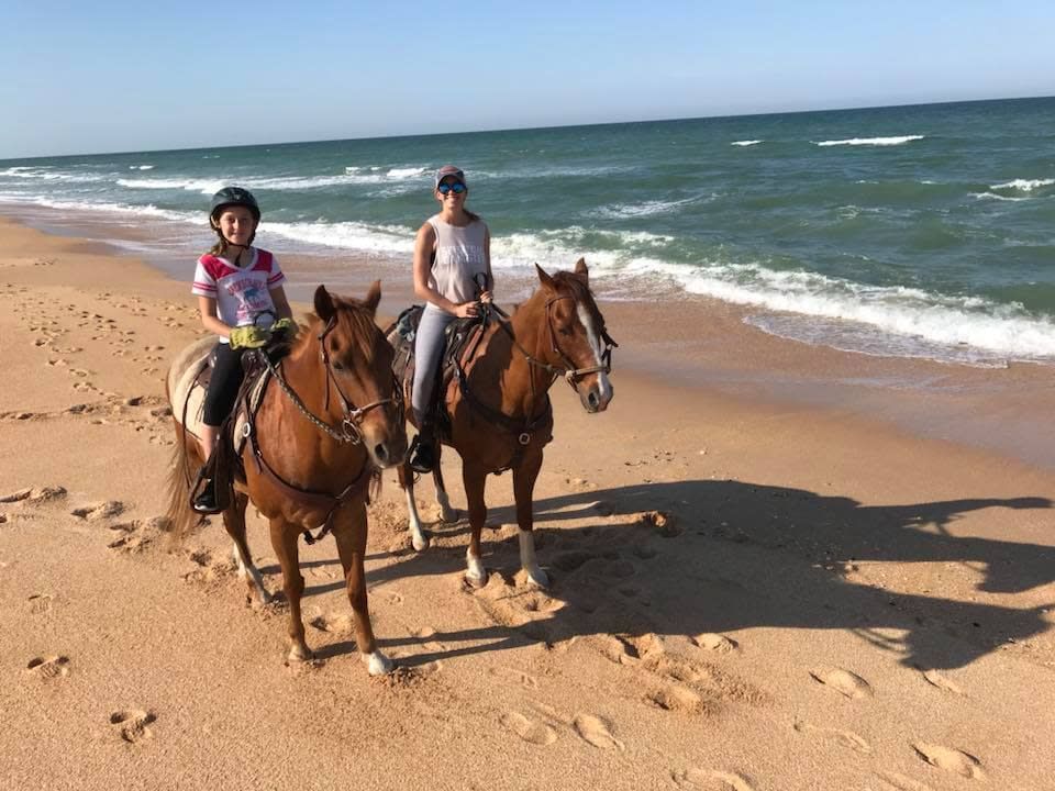 Two people riding horses on a beach