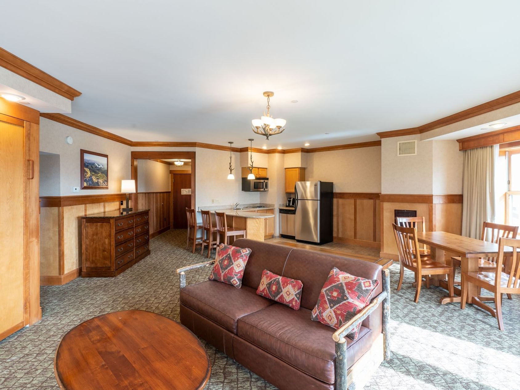 A spacious suite living area featuring a kitchen, dining table and leather couch at Lake Placid Club Grandview
