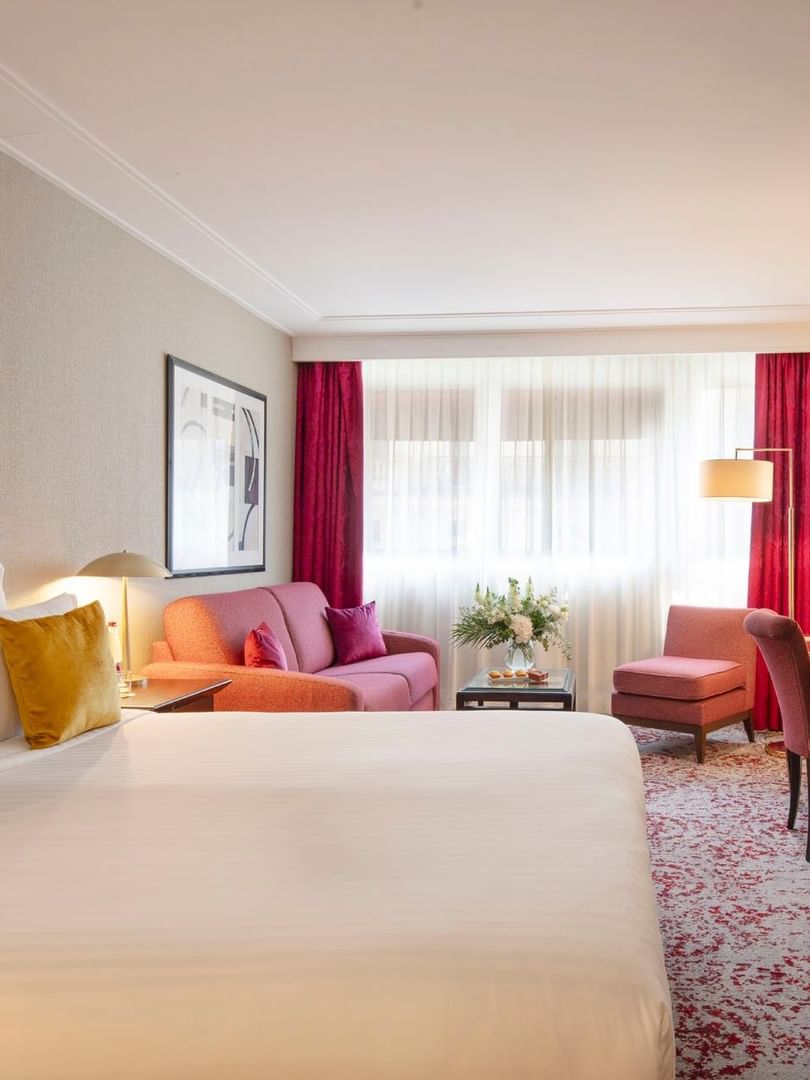 Chambre Executive avec grand lit, coin salon et fenêtre à l'hôtel Warwick Champs-Élysées à Paris.