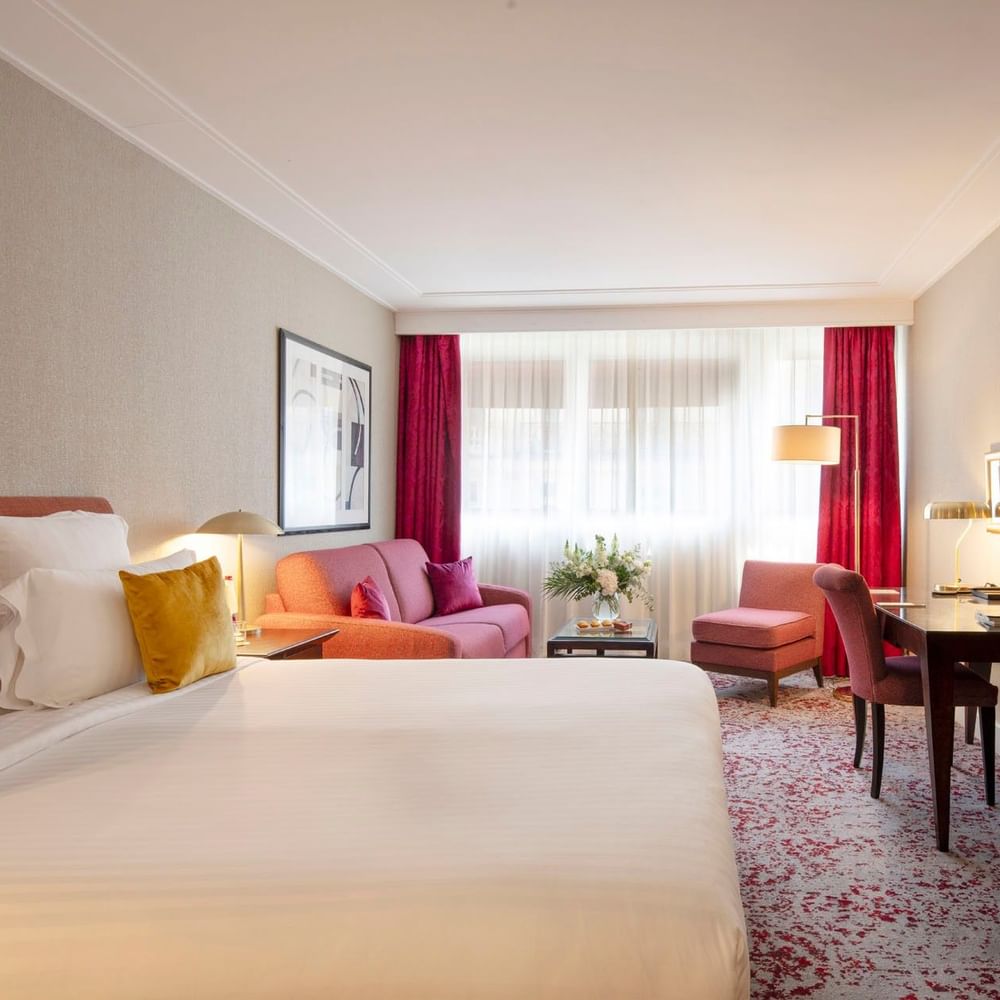 Chambre Executive avec grand lit, coin salon et fenêtre à l'hôtel Warwick Champs-Élysées à Paris.
