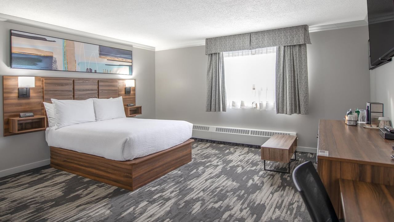Hotel room with large bed, desk, and window at Coast Dawson Creek Hotel.