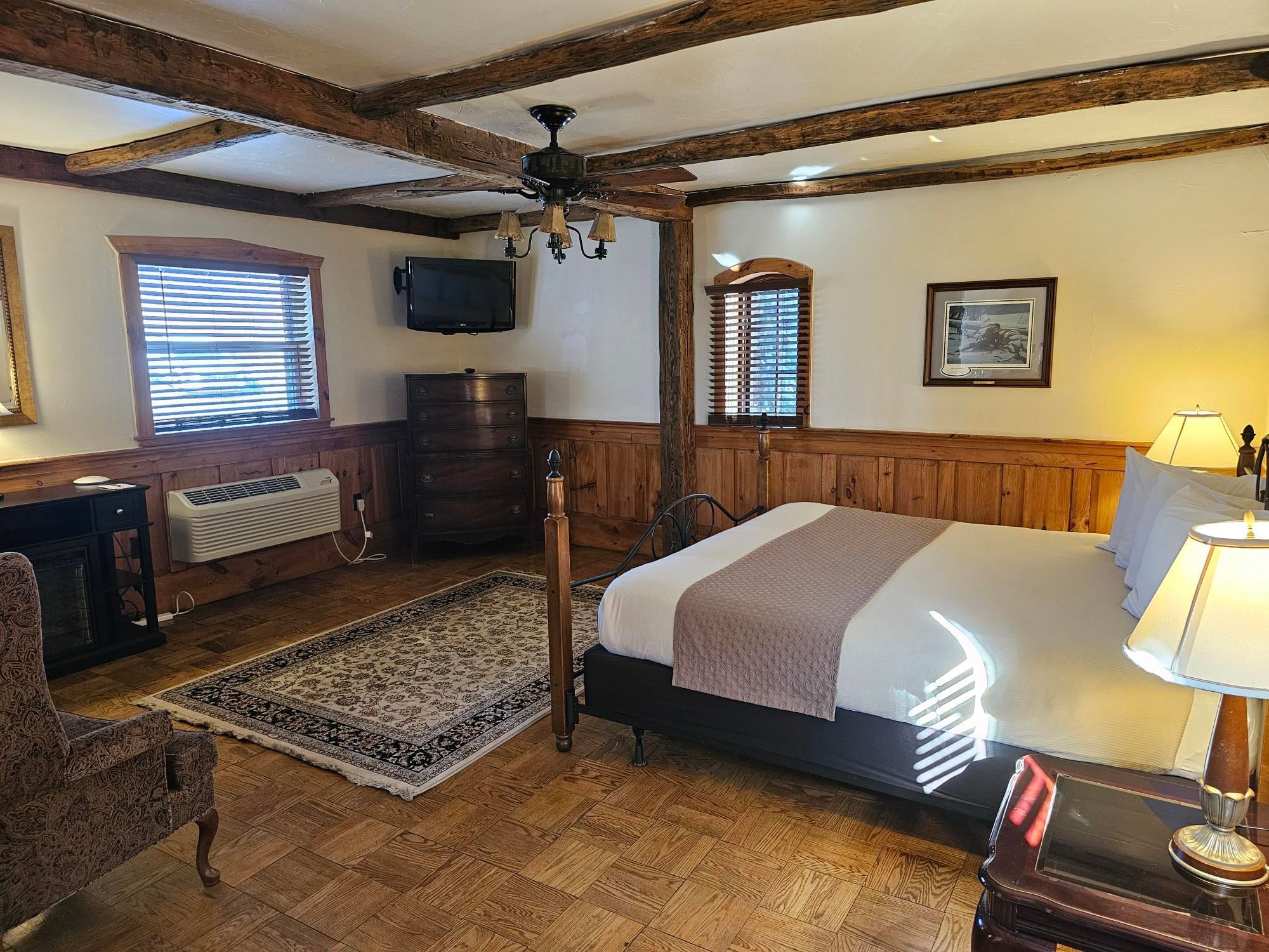 General's Lodge ADA complaint bedroom with a large bed, wooden furniture, carpet, and TV at The Lodges at Gettysburg.