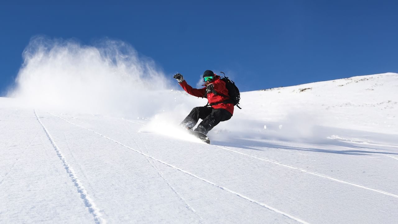 Snowboarder rides down snowy slope.