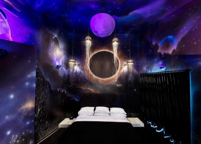 Cosmic-themed Galileo's Gate featuring glowing jellyfish lights, and a bed with black accents at The Roxbury