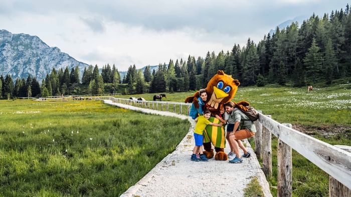 A family posing for a photo with a mascot, Falkensteiner Hotels