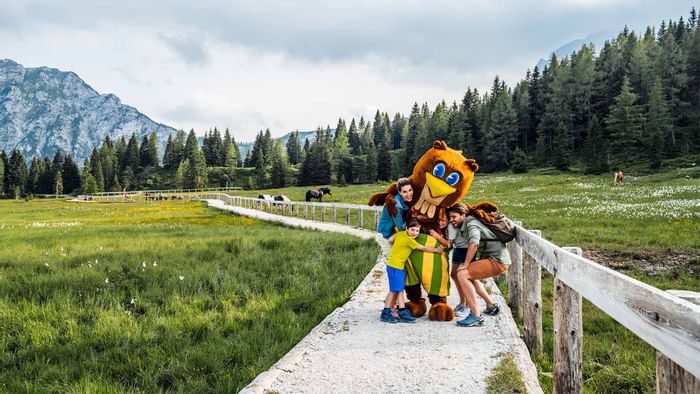 Family posing for a photo with a mascot at Falkensteiner Hotels & Residences